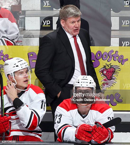 Head coach Bill Peters of the Carolina Hurricanes talks to his players as Andrej Nestrasil and Brock McGinn sit on the bench during the game against...