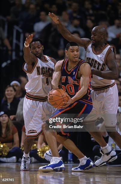 Allan Houston of the New York Knicks moves to hand off the ball as he is guarded by George McCloud and Anthony Goldwire of the Denver Nuggets at the...