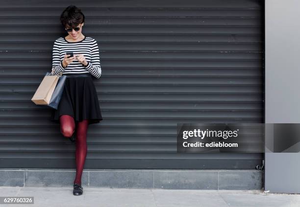 woman looking at mobile phone - shop shutter stock pictures, royalty-free photos & images