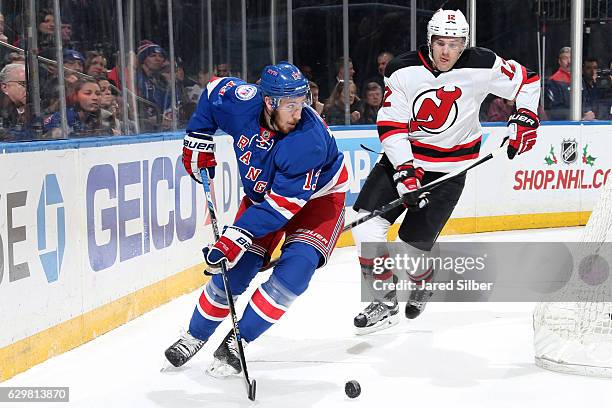 Kevin Hayes of the New York Rangers skates with the puck against Ben Lovejoy of the New Jersey Devils at Madison Square Garden on December 11, 2016...