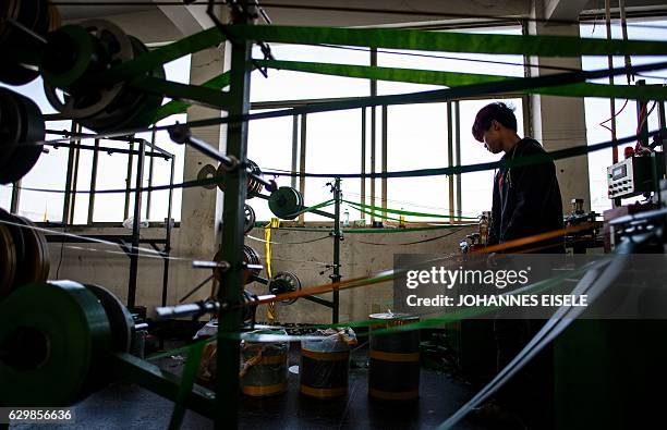 This picture taken on December 7, 2016 shows a worker operating a machine producing fake "branches" in Sun Xudan's artificial Christmas tree factory...