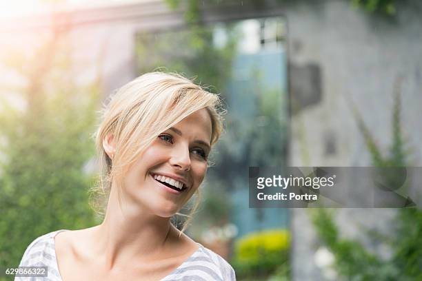 cheerful young woman looking away at yard - beautiful blondes stockfoto's en -beelden