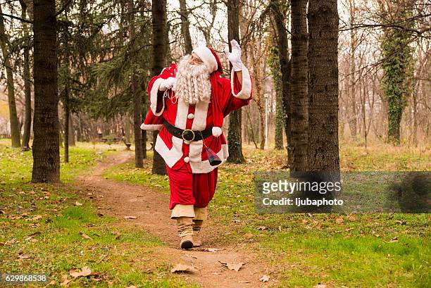 santa claus waving  in forest  with a bag of gifts - claus lange stock pictures, royalty-free photos & images