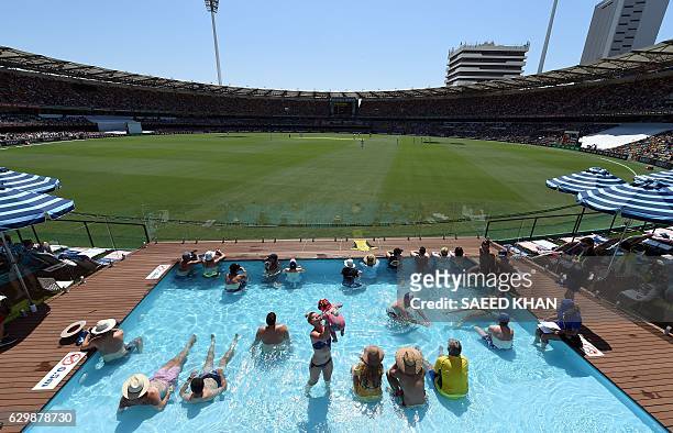 Spectators watch the first day-night cricket Test between Australia and Pakistan from the wading pool inside the Gabba stadium in Brisbane on...