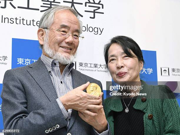 Holding his Nobel medal, laureate Yoshinori Ohsumi attends a press conference with his wife Mariko at Tokyo's Haneda airport on Dec. 14 after...