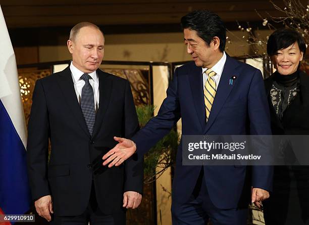 Russian President Vladimir Putin shakes hands with Japanese Prime Minister Shinzo Abe as his wife Akie Abe looks on during the official reception...