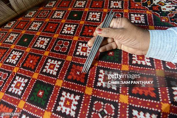 Indian artist Satishchandra Salvi works on a 'Patola Saree' at a workshop in Patan some 120kms. From Ahmedabad on December 15, 2016. The Patola Saree...