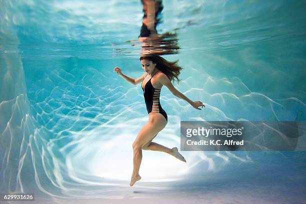 portrait of a female model underwater in a swimming pool with a black background in san diego, california. - kids swimsuit models stockfoto's en -beelden