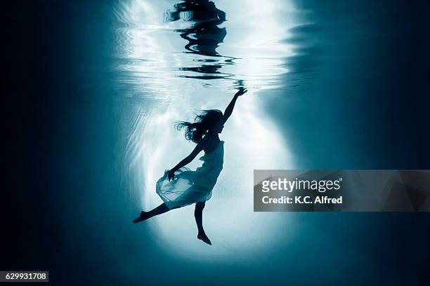 silhouette portrait of a female model underwater appearing to dance in a swimming pool in san diego, california. - swimsuit models girls stock pictures, royalty-free photos & images