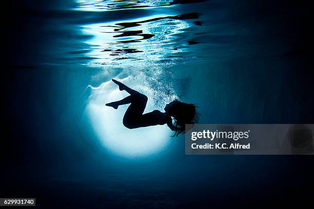 silhouette portrait of a female model underwater appearing to dance in a swimming pool in san diego, california. - kids swimsuit models stockfoto's en -beelden