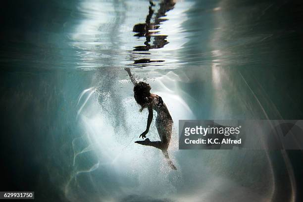 silhouette portrait of a female model underwater appearing to dance in a swimming pool in san diego, california. - swimsuit models girls stock pictures, royalty-free photos & images