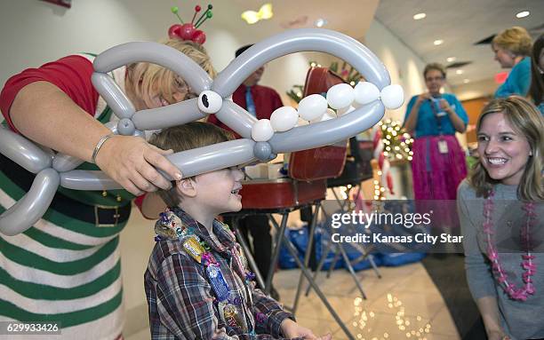 Balloon artist Johnna Perry places a shark on Donovan Campbell as his mother, Kelli Campbell, lookes on during festivities at the Snowball Express on...