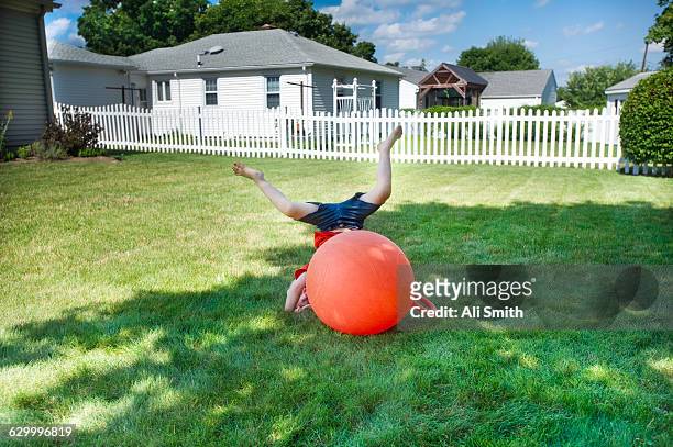 boy bouncing on orange ball - bouncing stockfoto's en -beelden