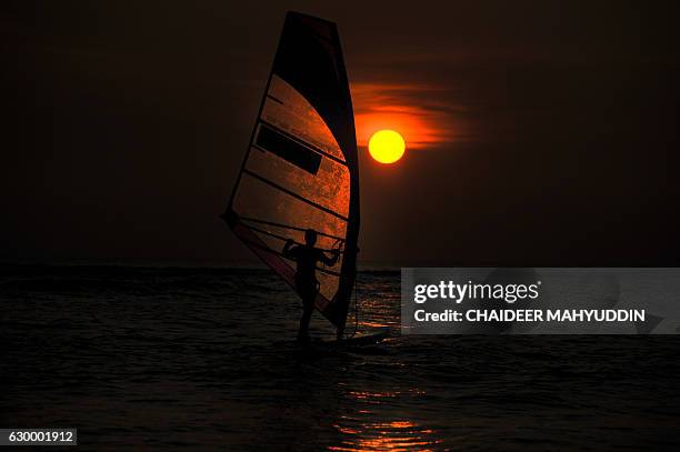 In this photograph taken on December 15, 2016 an Acehnese windsurfs at Lhoknga, in Aceh province. Lhoknga is one of Aceh west coast area which was...