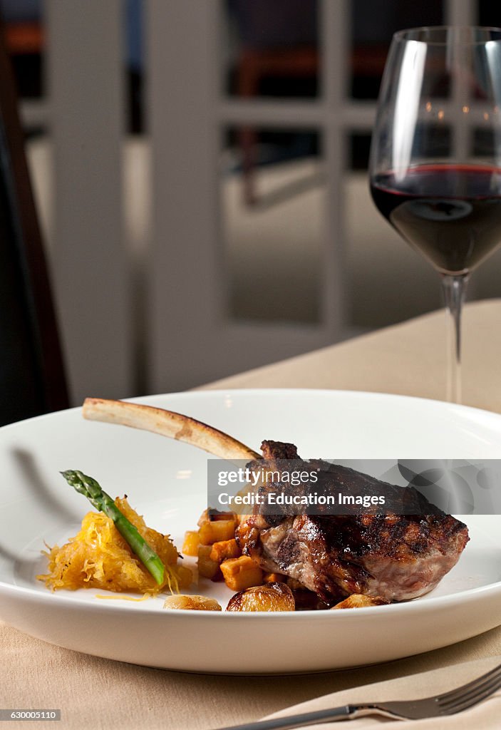 Bone in rib eye steak with red wine on white plate