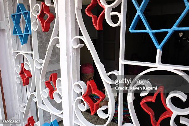 Behind the windows of A Jewish home in the old neighborhood docorated with the Star of David an old Jewish woman sat on a chair reads the Torah on...