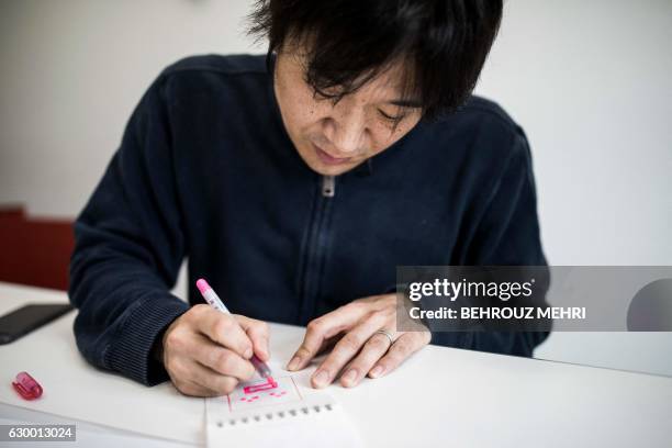 Japanese Shigetaka Kurita, the man who created emoji charachters, draws an emoji charachter during an interview with AFP in Tokyo on November 30,...