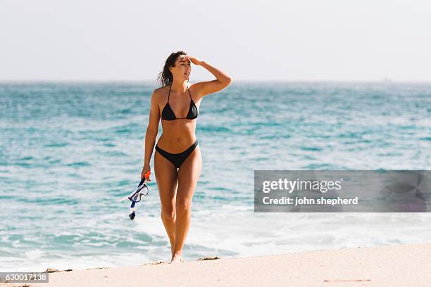 mujer joven caminando por la playa de porthcurno. - biquini negro fotografías e imágenes de stock