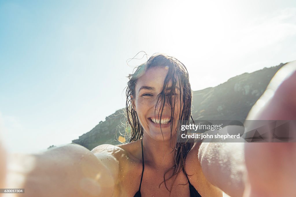 Junge Frau, die ein POV Selfie Foto am Strand von Porthcurno macht.
