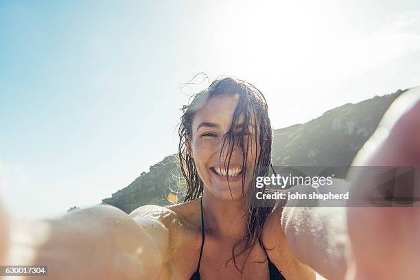 junge frau, die ein pov selfie foto am strand von porthcurno macht. - lands end cornwall stock-fotos und bilder