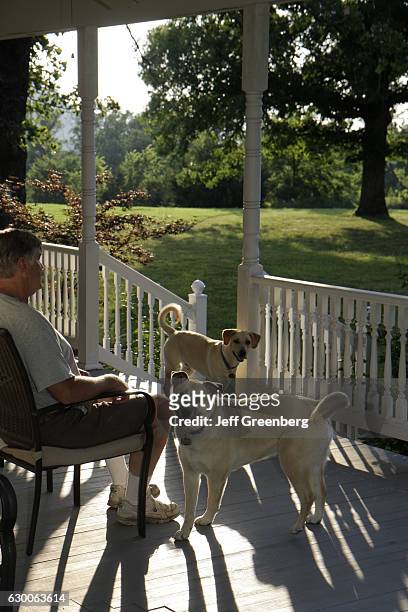 Man sat with two dogs on the porch at Country Oaks Bed and Breakfast.