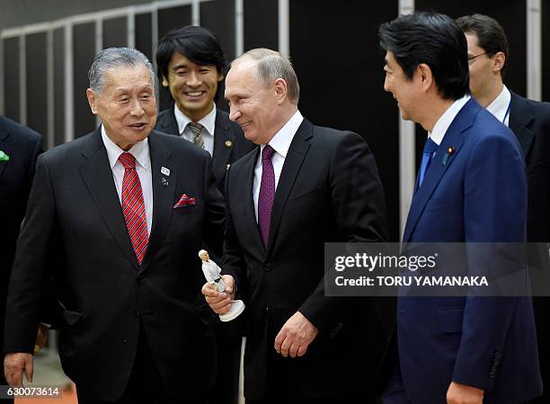 Russian President Vladimir Putin holds a figure of Jigoro Kano, the founder of judo, received from former Japanese Prime Minister Yoshiro Mori beside...
