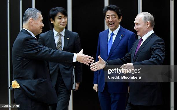 Vladimir Putin, Russia's president, right, shakes hands with Yoshiro Mori, Japan's former prime minister, left, as Shinzo Abe, Japan's prime...