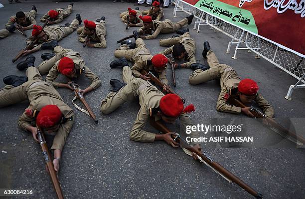 Pakistani school students dressed in army uniforms act in a drama in Karachi on December 16 as they pay tribute to victims on the second anniversary...