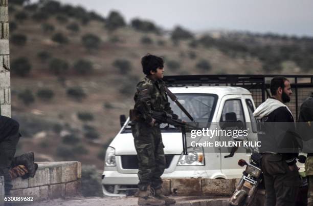 Young Syrian rebel fighter holding a weapon waits on a road in Bab al-Hawa near the Syrian border with Turkey on December 16, 2016. The Syrian...