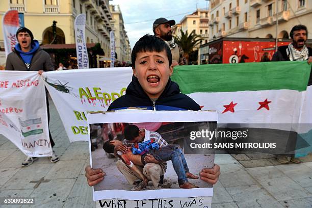 Syrian boy holds a photograph showing a man carrying the dead body of a boy in Syria, during a demonstration in support of the inhabitants of the...