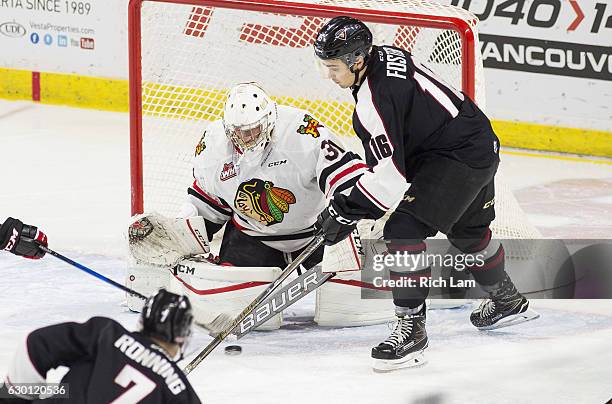 Goalie Cole Kehler of the Portland Winterhawks stops the shot of Ty Ronning of the Vancouver Giants while Thomas Foster looks for a rebound during...