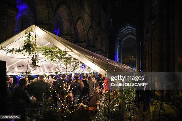 Members of the public experience the Leeds Hidden Christmas Market in the ruins of Kirkstall Abbey in Leeds, northern England on December 16, 2016....