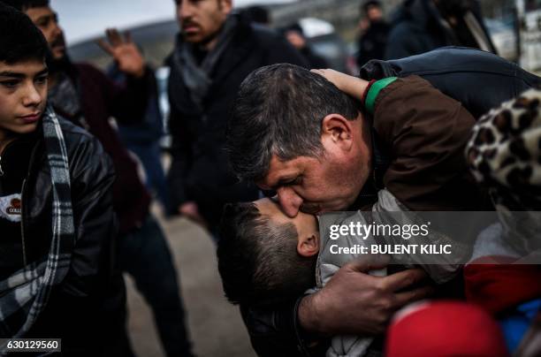 Syrian father Ali embraces one of his children, Zeyn, upon their arrival from the Syrian city of Idlib to the Turkish crossing gate of Cilvegozu in...