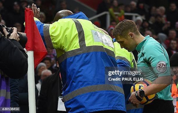 Officials shield English referee Crais Pawson from coins being thrown by Leicester City fans as he leaves the pitch at half-time, during the English...