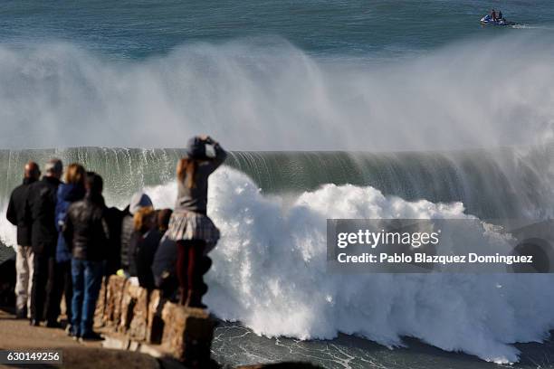 Members of the public watch big waves as surfers try to catch them at Praia do Norte on December 17, 2016 in Nazare, Portugal. Nazare's giant waves...