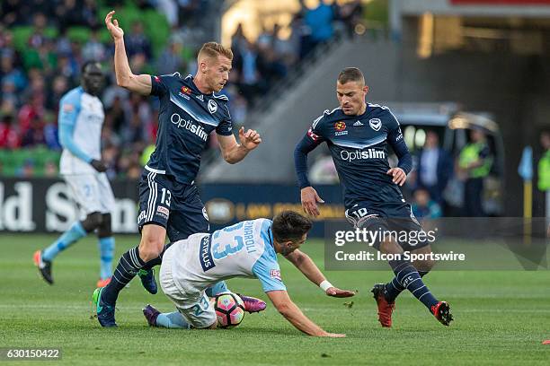 Bruno Fornaroli of Melbourne City falls after a contest with Oliver Bozanic of Melbourne Victory and James Troisi of Melbourne Victory during the...