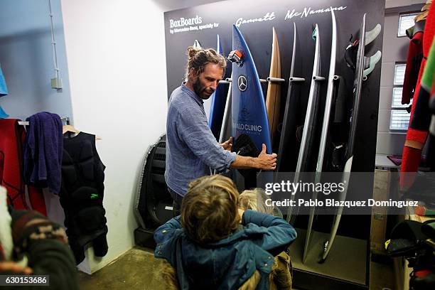 Portuguese surfer Hugo Vau shows his boards to some children at his warehouse after a big waves session on December 17, 2016 in Nazare, Portugal....