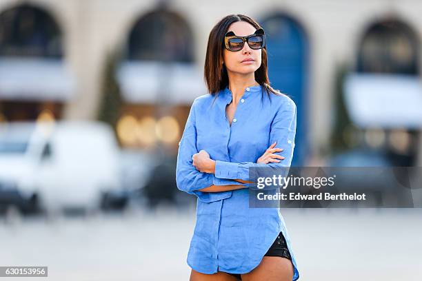 Patricia Gloria Contreras, model and fashion blogger, is wearing a Bagutta blue blouse, a black short, Aquazurra red shoes, and Anna Karin Karlsson...