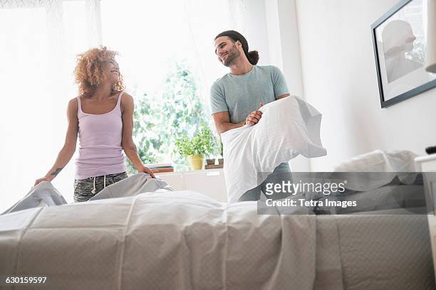 young couple making bed in morning - making stock pictures, royalty-free photos & images