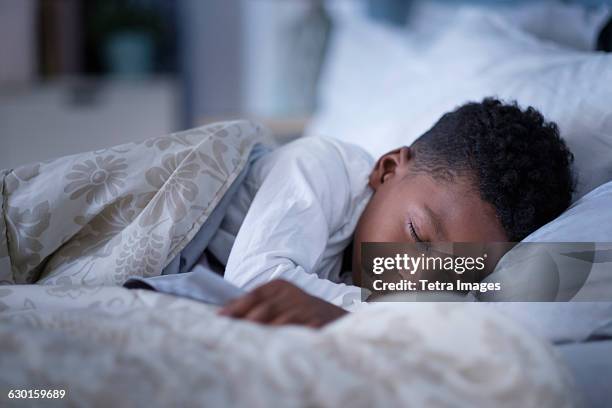 boy (6-7) sleeping in bed - sleeping boys stockfoto's en -beelden