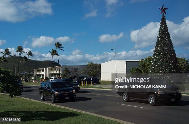 President Barack Obama's motorcade drives past a Christmas tree on December 17, 2016 at Marine Corps Base Hawaii as he departs after playing golf on...