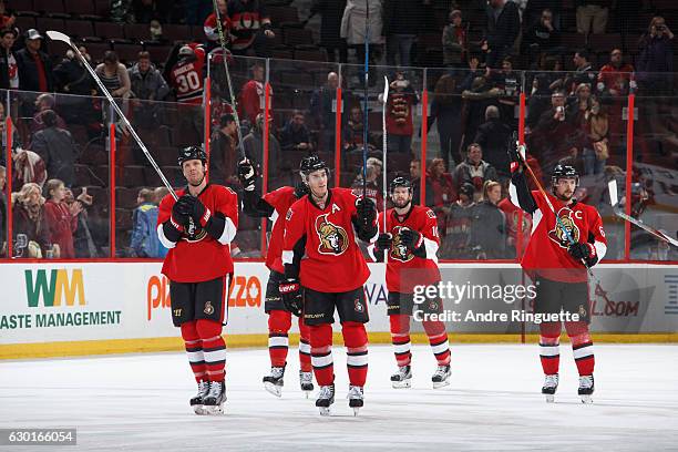 Marc Methot, Kyle Turris, Tom Pyatt and Erik Karlsson of the Ottawa Senators raise their sticks to salute the fans after a win against the New Jersey...