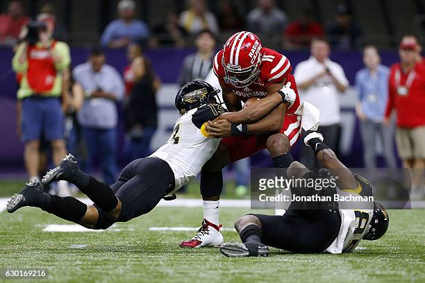 Picasso Nelson Jr. #13 of the Southern Miss Golden Eagles and Ja'Boree Poole sack Anthony Jennings of the Louisiana-Lafayette Ragin Cajuns during the...