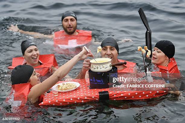 People eat a cheese fondue as they swim during the 78th "Coupe de Noel" swimming race in the Lake Geneva, on December 18, 2016 in Geneva. More than...