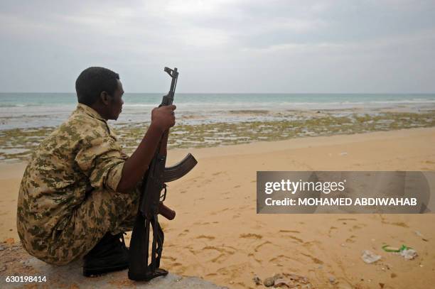 Member of the Somali security forces stands gard on the beach on the coast of Qaw, in Puntland, northeastern Somalia on December 2016. Armed...