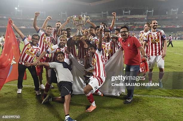 Atletico de Kolkata players celebrate with the trophy after winning the Indian Super League final football match against Kerala Blasters FC at the...