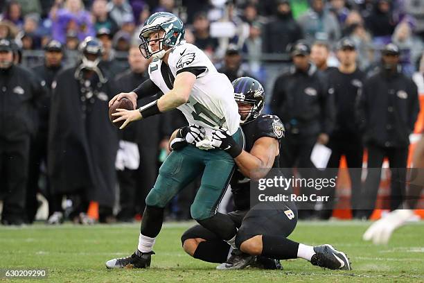 Quarterback Carson Wentz of the Philadelphia Eagles is pulled down by defensive end Lawrence Guy of the Baltimore Ravens in the second quarter at M&T...