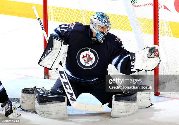 Goaltender Connor Hellebuyck of the Winnipeg Jets makes a glove save during third period action against the Colorado Avalanche at the MTS Centre on...