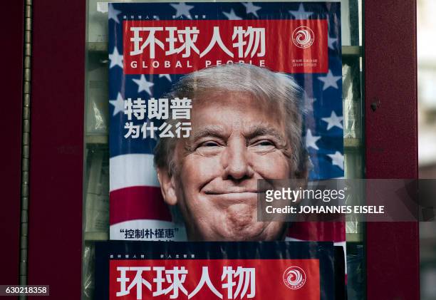 This picture taken on December 14, 2016 shows a advertisement for a magazine featuring US President-elect Donald Trump on the cover at a news stand...