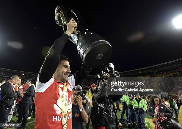 Jonathan Agudelo of Santa Fe lifts the trophy to celebrate after winning a second leg final match between Santa Fe and Deportes Tolima as part of...
